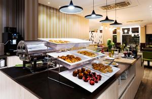 un buffet avec plusieurs plateaux de nourriture sur un comptoir dans l'établissement B&B HOTEL Vigo, à Vigo