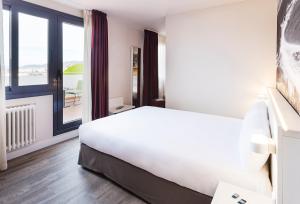 a white bed sitting in a room next to a window at B&B Hotel Vigo in Vigo