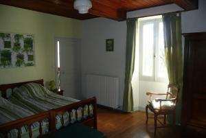a bedroom with a bed and a window and a chair at Domaine Serrot in Saint-Élix-Theux
