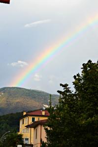 un arco iris en el cielo con un edificio y árboles en B&B Arcobaleno, en Vittorio Veneto