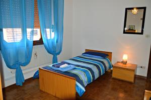 ヴィットリオ・ヴェネトにあるB&B Arcobalenoのベッドルーム1室(青いカーテンと鏡付きのベッド1台付)