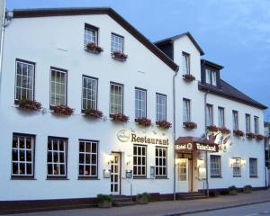 un bâtiment blanc avec un restaurant dans une rue dans l'établissement Hotel Hinz, à Bad Oldesloe
