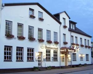 a white building with a restaurant on a street at Hotel Hinz in Bad Oldesloe