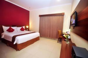 Nueve Malioboro Hotel Yogyakarta في يوغياكارتا: غرفة نوم بسرير وتلفزيون بشاشة مسطحة