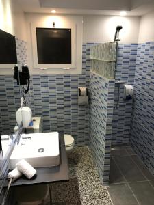 a bathroom with a sink and a toilet and a tv at Hotel Gri-Mar in Llança +29 photos