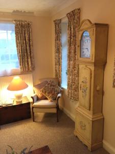 uma sala de estar com um relógio avô e uma cadeira em Beech View Cottage em Downham Market