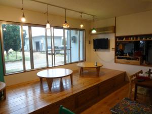 a living room with two tables and a large window at Minshuku Namisou in Iriomote