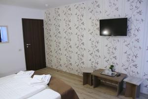 a bedroom with a bed and a tv on a wall at Pensiunea Argesu ** in Sinaia