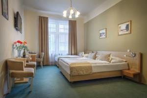 Un dormitorio con dos camas y una silla y una ventana. en Hotel Taurus, en Praga