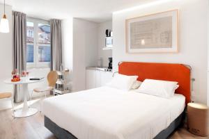 a bedroom with a white bed and a small kitchen at LSA Ascensor da Bica by Numa in Lisbon