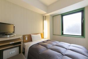 a bedroom with a bed and a television in it at R&B Hotel Shin Yokohama Ekimae in Yokohama