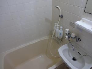 a bathroom with a bath tub and a sink at Minshuku Namisou in Iriomote