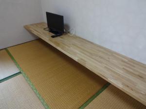 a wooden table with a laptop sitting on top of it at Minshuku Namisou in Iriomote
