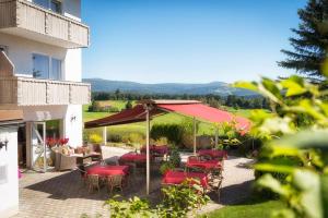 un patio con sillas rojas y sombrilla en Der Wieshof, en Riedlhütte