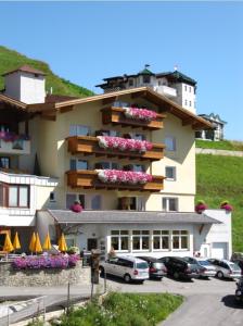 duży budynek z samochodami zaparkowanymi przed nim w obiekcie Hotel Garni Panorama w mieście Serfaus