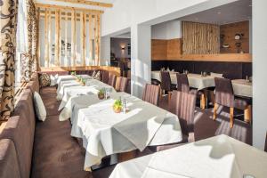 a restaurant with white tables and chairs and windows at Hotel Garni Panorama in Serfaus