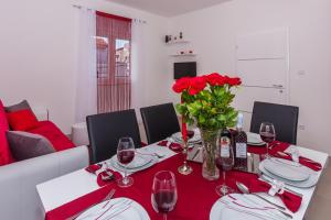 a dining room table with red flowers and wine glasses at Apartment Ema in Split