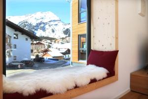 asiento junto a la ventana con vistas al invierno de una montaña cubierta de nieve en LEHNER Panorama Alpensuiten, en Berwang