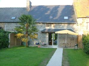 a stone house with a table and an umbrella at Gîtes du Vieux Presbytère in Baguer-Pican