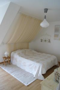 a bedroom with a white bed with a canopy at Gîtes du Vieux Presbytère in Baguer-Pican