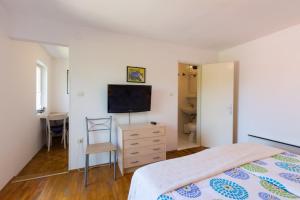 sypialnia z łóżkiem i telewizorem na komodzie w obiekcie Aloe w miejscowości Mali Lošinj