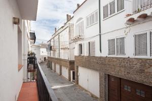 a narrow alley with white buildings and a fence at Akira Flats Cadaqués Apartments in Cadaqués
