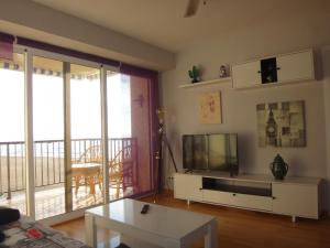 a living room with a couch and a tv and a table at Torremar I in Torredembarra