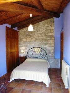 1 dormitorio con 1 cama en una pared de piedra en Casa Mur Artesania, en Lecina