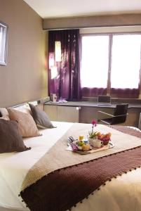 a hotel room with a bed with a tray of fruit on it at Hotel Gratte-Ciel Ariana in Villeurbanne