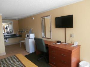 a hotel room with a desk and a bed and a television at America's Best Value Inn Conyers in Conyers