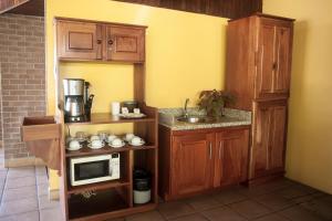 a kitchen with wooden cabinets and a sink and a microwave at Hotel La Punta in Puntarenas