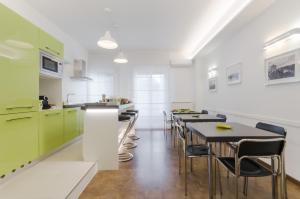 eine Küche mit grünen Schränken, Tischen und Stühlen in der Unterkunft Le Stanze Sul Corso in Pescara