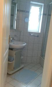 ein weißes Bad mit einem Waschbecken und einem Fenster in der Unterkunft 2 Zimmer Kursuite Bad Füssing in Bad Füssing