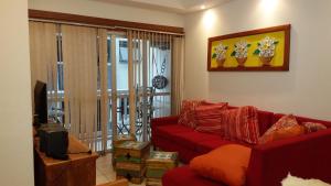 salon z czerwoną kanapą i telewizorem w obiekcie Apartamento com Terraço no Guarujá w mieście Guarujá