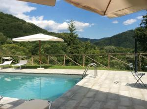 a swimming pool with chairs and an umbrella at Tuscany Meanders in Bagni di Lucca