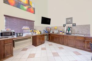 a large kitchen with wooden cabinets and a tv at Days Inn by Wyndham Lamar in Lamar