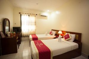 Pokój hotelowy z 2 łóżkami, biurkiem i lustrem w obiekcie SÀI GÒN - BẠC LIÊU Hotel w mieście Bạc Liêu
