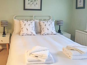 a bedroom with a white bed with towels on it at Ivy Cottage in Aldeburgh