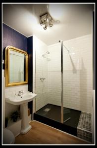a bathroom with a sink and a shower with a mirror at Hotel Le Prieuré et La Résidence in Amiens