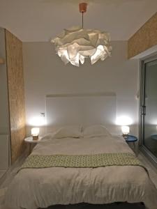 a bedroom with a large bed and a chandelier at Superbe appartement sur la plage - Le Zénith in Palavas-les-Flots