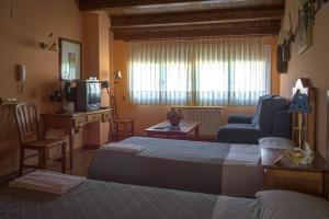 - une chambre avec un lit, un canapé et une télévision dans l'établissement La Posada de Clotilde, à Cella