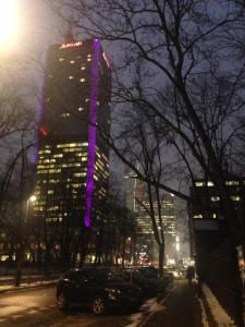 un edificio alto con luces moradas en él por la noche en Luxury Apartment - Hoza 55, en Varsovia
