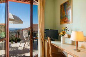 a room with a desk with a television and a balcony at Duca Del Mare - Hotel Di Nardo group in Massa Marittima
