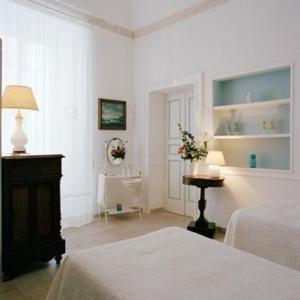 マルティナ・フランカにあるヴィラッジョ イン カーゼ スパルセ ネル チェントロ ストーリコの白いベッドルーム(ベッド2台、花のテーブル付)