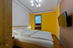 ソポトにあるImperial Apartments Aquarius IIIのベッドルーム1室(黄色い壁のベッド1台、テレビ付)
