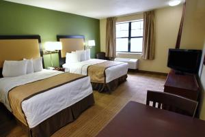 a hotel room with two beds and a flat screen tv at Extended Stay America Suites - Detroit - Roseville in Roseville