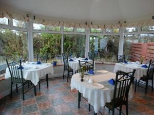 uma sala de jantar com mesas, cadeiras e janelas em Dunlavin House - Aidan OBrien em Dingle
