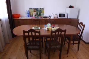 a wooden table with chairs and a table and a kitchen at Gvirilas Sakhli Guest House in Khashuri