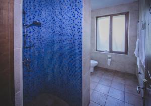 bagno con doccia piastrellata blu e servizi igienici di Marshal Resort Kobuleti a Kobuleti