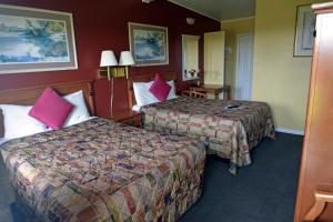 um quarto de hotel com duas camas com almofadas cor-de-rosa em Gateway Inn em Red Bluff